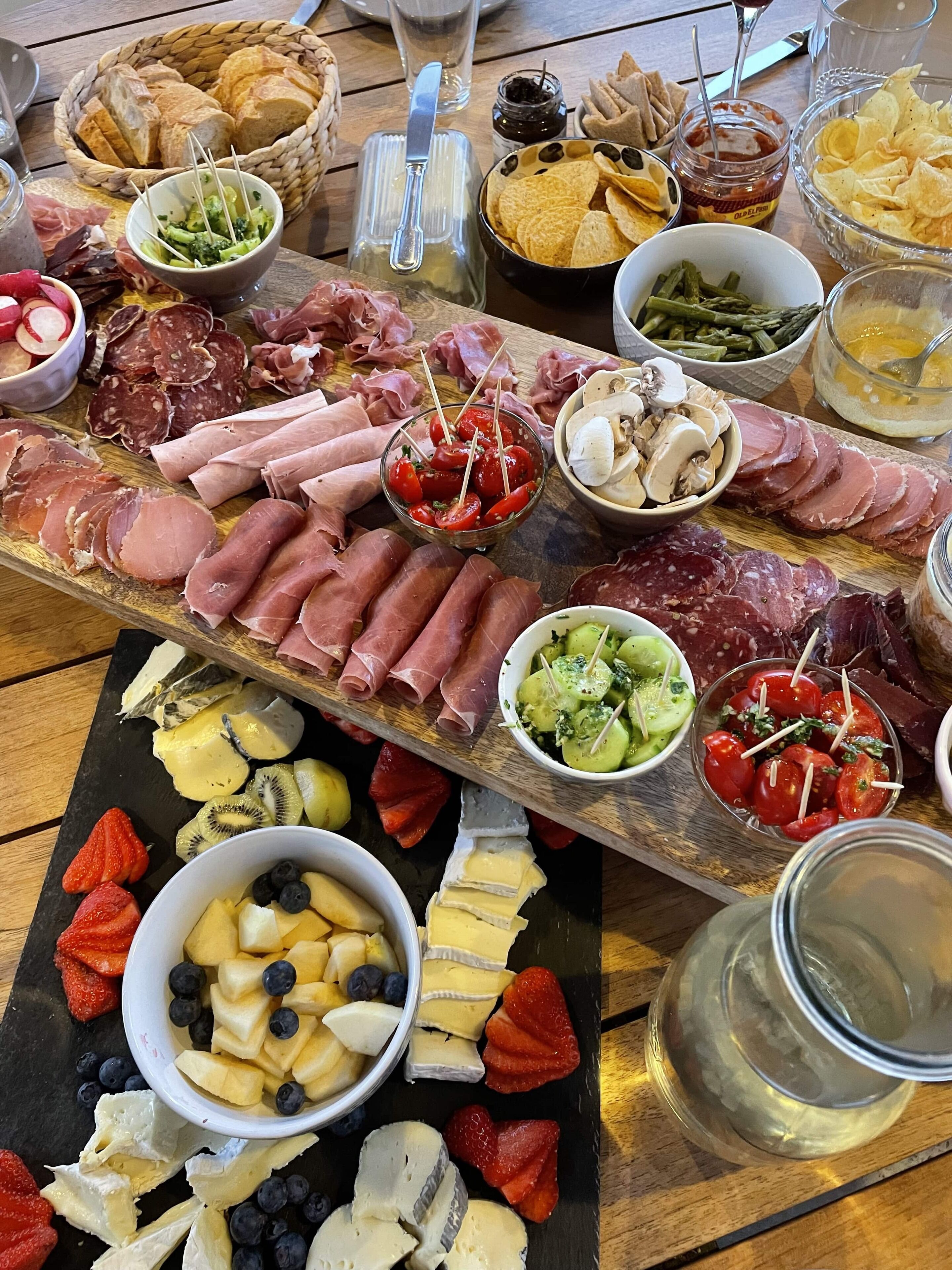 A charcuterie board with various meats, cheeses, and fruits.