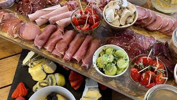 A charcuterie board with various meats, cheeses, and fruits.