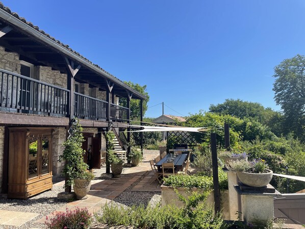 A stone building with a balcony, outdoor seating, and a garden area. - Charming 4* gîte with private pool&jacuzzi 11 bedrooms/10 bathrooms (Touffailles)