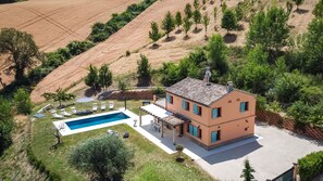 Enjoy a serene retreat in this two-story house surrounded by lush greenery and a pool with sunken seating area.