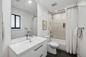 Un baño moderno con tocador blanco, inodoro, bañera y ducha.