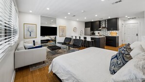 Ett modernt hotellrum med en säng, en soffa, en matplats och ett kök.