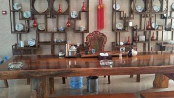 A long wooden table with various items on it, surrounded by shelves with clocks and decorative items.