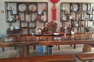 A long wooden table with various items on it, surrounded by shelves with clocks and decorative items.