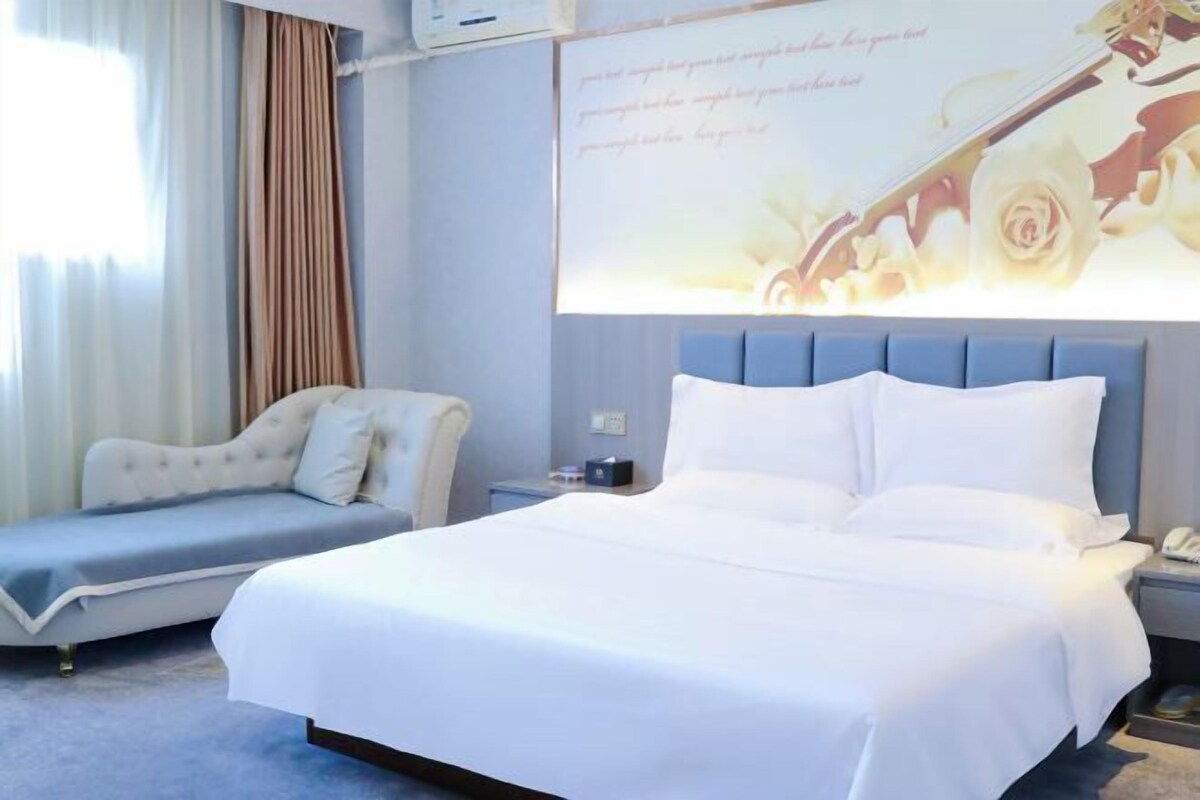 Une chambre d’hôtel comprenant un lit, un canapé, une table de chevet et un écran fixé au mur, sur lequel est affiché un motif floral.