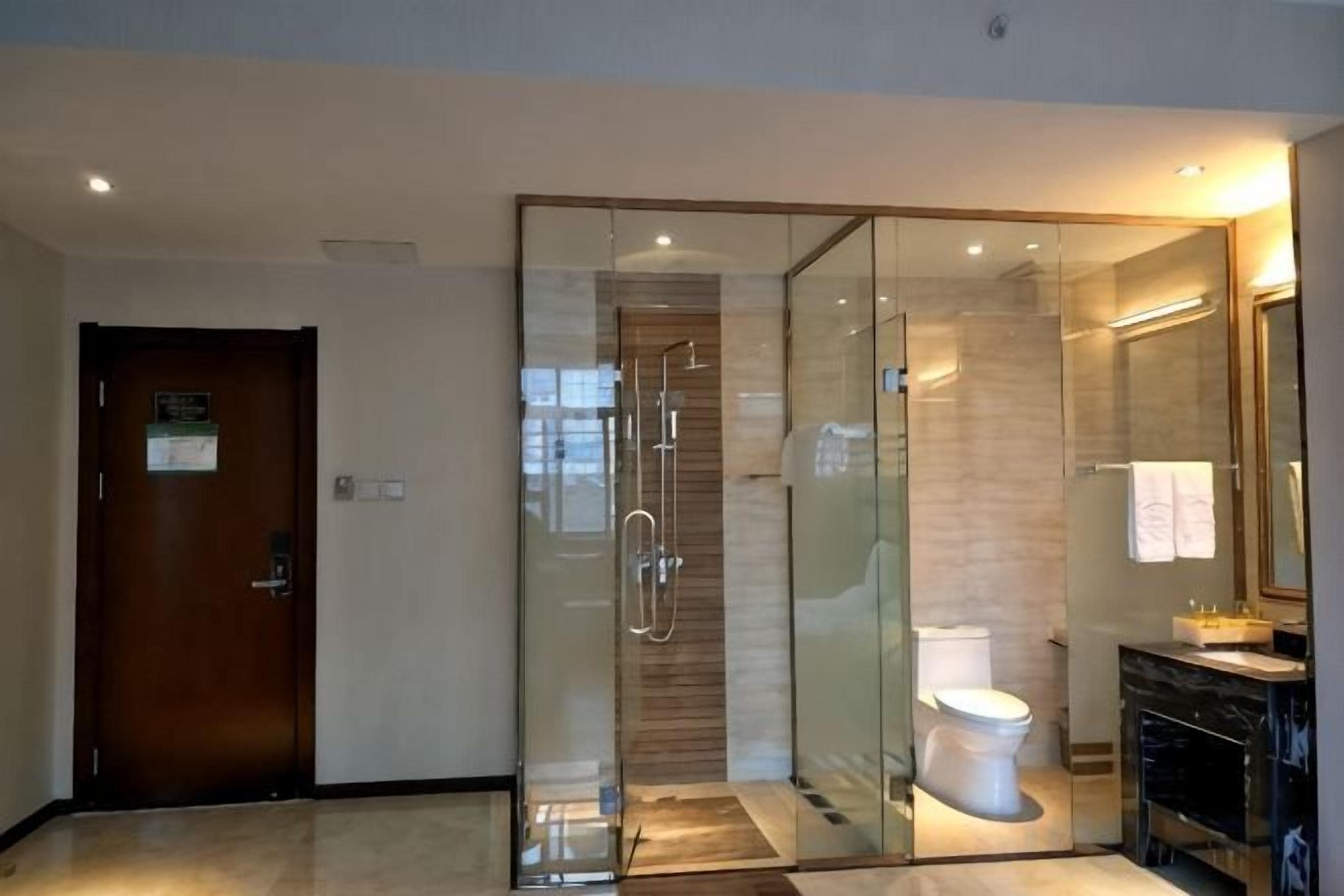Une salle de bain moderne avec une douche à parois de verre, des toilettes et un meuble-lavabo avec un miroir.