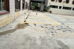 A courtyard with a tiled wall, a yellow line marking, and a red cone. - Impression Hotel (Wenshan City)