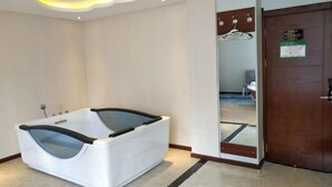 A modern bathroom with a large bathtub, a mirror, and a wooden door. - Impression Hotel (Wenshan City)