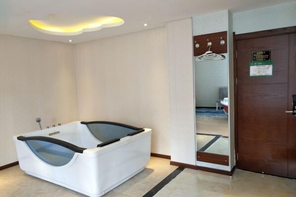 Une salle de bain moderne avec une grande baignoire, un miroir et une porte en bois.