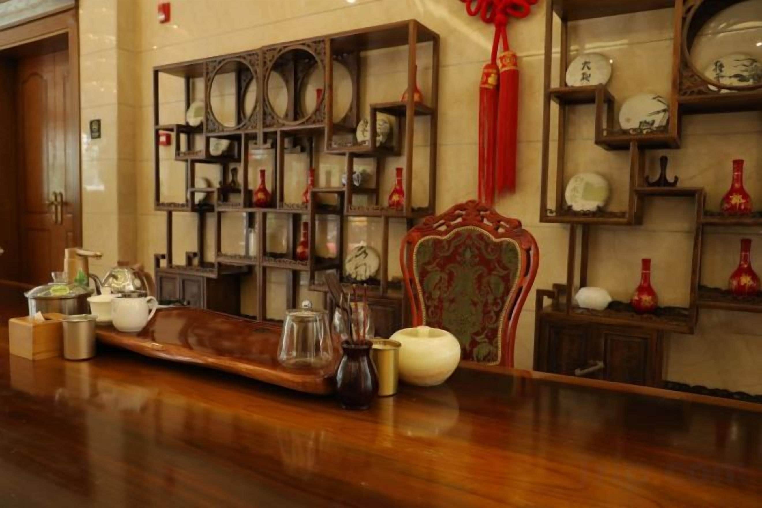 A room with a wooden floor, a decorative chair, and shelves with various items.