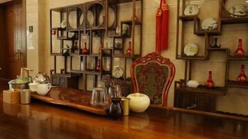A room with a wooden floor, a decorative chair, and shelves with various items.