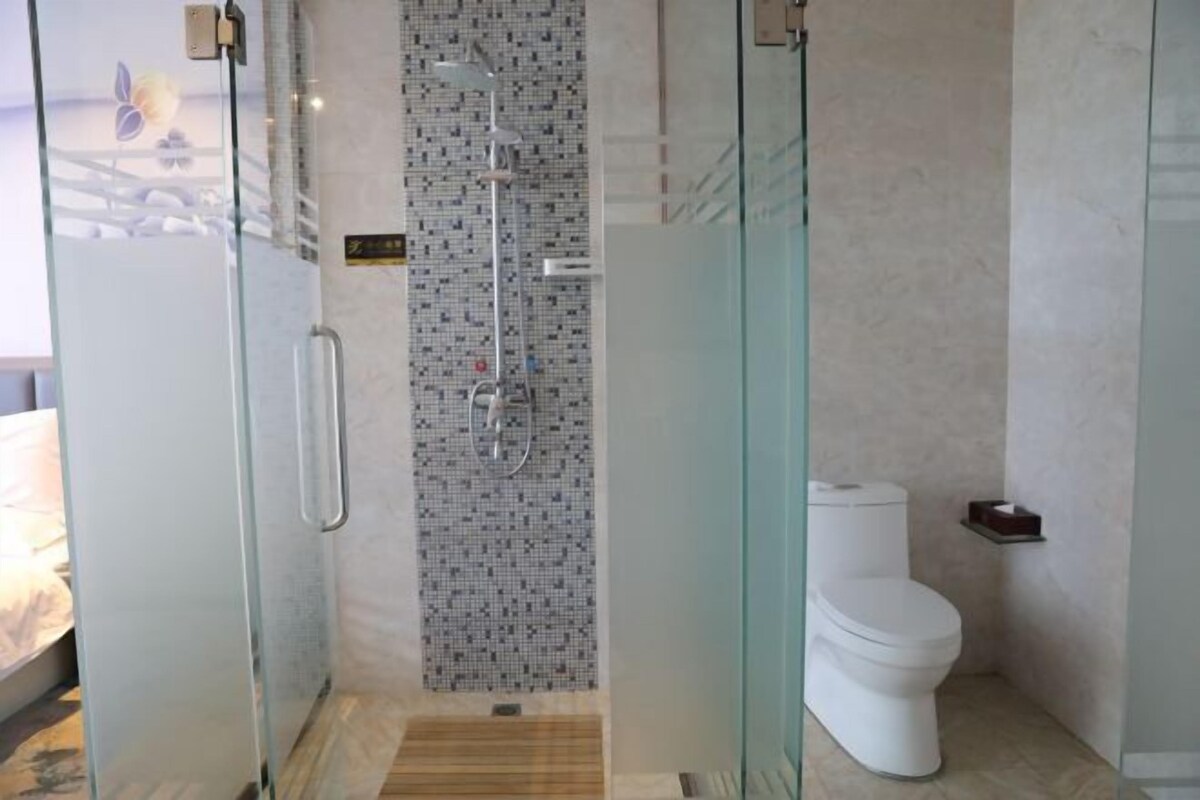 Une salle de bain moderne avec une douche à parois de verre, des toilettes et une petite étagère contenant des articles de toilette.