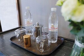 Un plateau en métal sur lequel on trouve des verres en verre transparent, une carafe en verre et deux bouteilles d’eau.