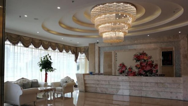 A spacious lobby with a marble floor, a grand chandelier, and a reception desk with a floral arrangement. - Impression Hotel (Wenshan City)