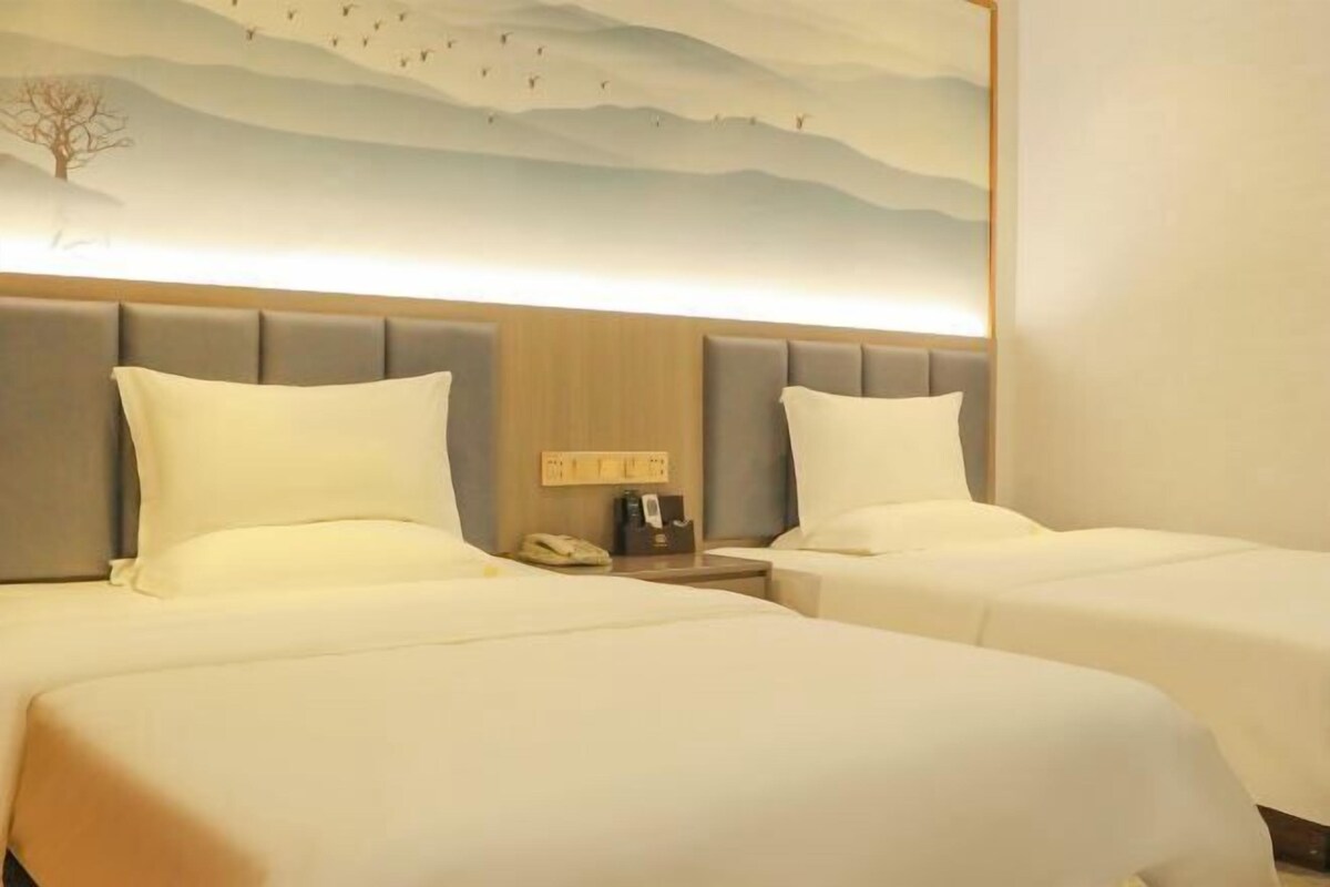 Une chambre d’hôtel avec deux lits, une tête de lit en bois, une table de chevet avec un téléphone et une fresque murale.