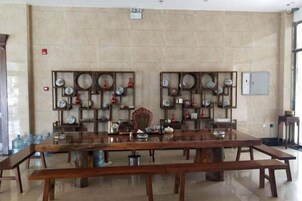 Un comedor con una larga mesa de madera, bancos y estanterías fijas con diversos objetos.