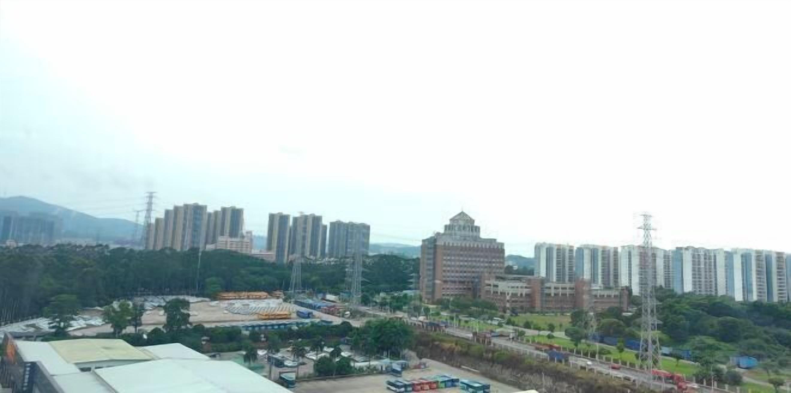 A residential area with high-rise buildings, a central plaza, and surrounding greenery.