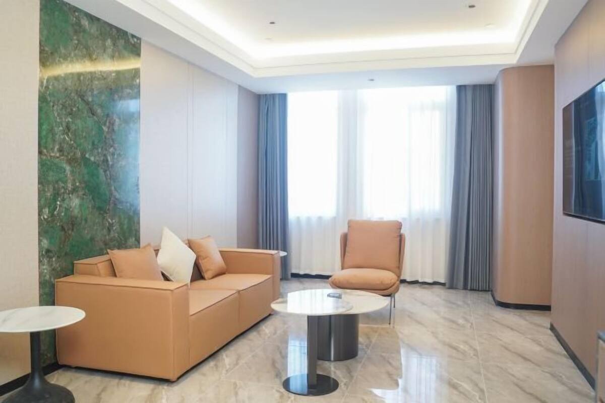 A modern hotel room with a sofa, armchair, and a small table.