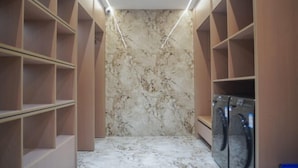 A laundry room with marble flooring, shelves, and a washing machine. - Kangtai Hotel (Hanggin Banner)