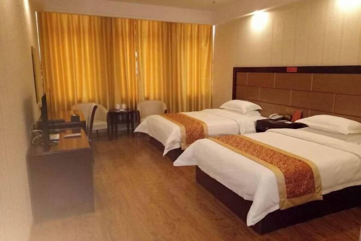 A hotel room with two beds, a desk, a chair, and a curtain.