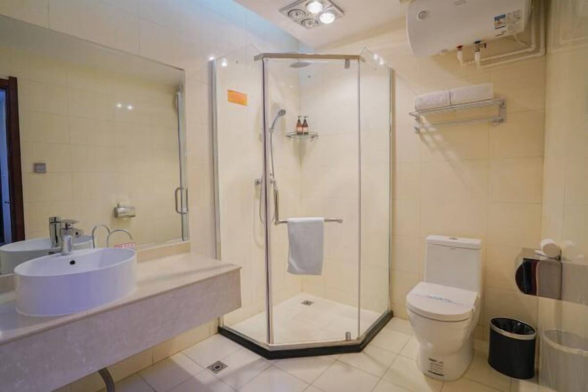 A modern bathroom with a glass-enclosed shower, a white sink, and a toilet.