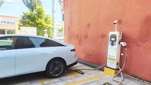 A white car parked at an electric vehicle charging station with a yellow line on the ground. - Kangtai Hotel (Hanggin Banner)