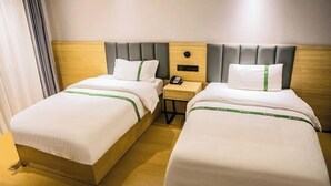A hotel room with two beds, a wooden headboard, a bedside table with a phone, and a nightstand. - GreenTree Inn Smart Choice Hotel (Changzhou Xixiashu Branch) (Huludao)