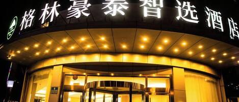 A hotel entrance with illuminated signage and a revolving door.