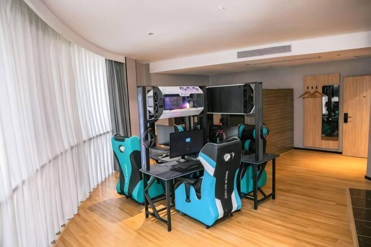 A hotel room with a gaming setup, a TV, and a wardrobe.