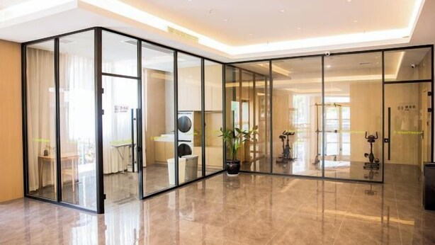 A modern hotel lobby with glass walls, a polished floor, and a potted plant. - GreenTree Inn Smart Choice Hotel (Changzhou Xixiashu Branch) (Huludao)