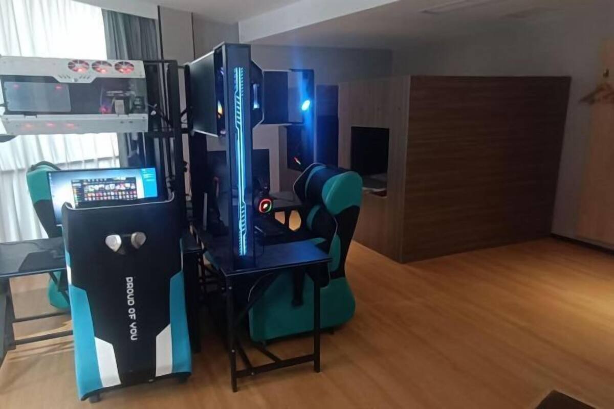 A gaming setup with a PC, monitor, and gaming chair in a room with wooden flooring and a window.