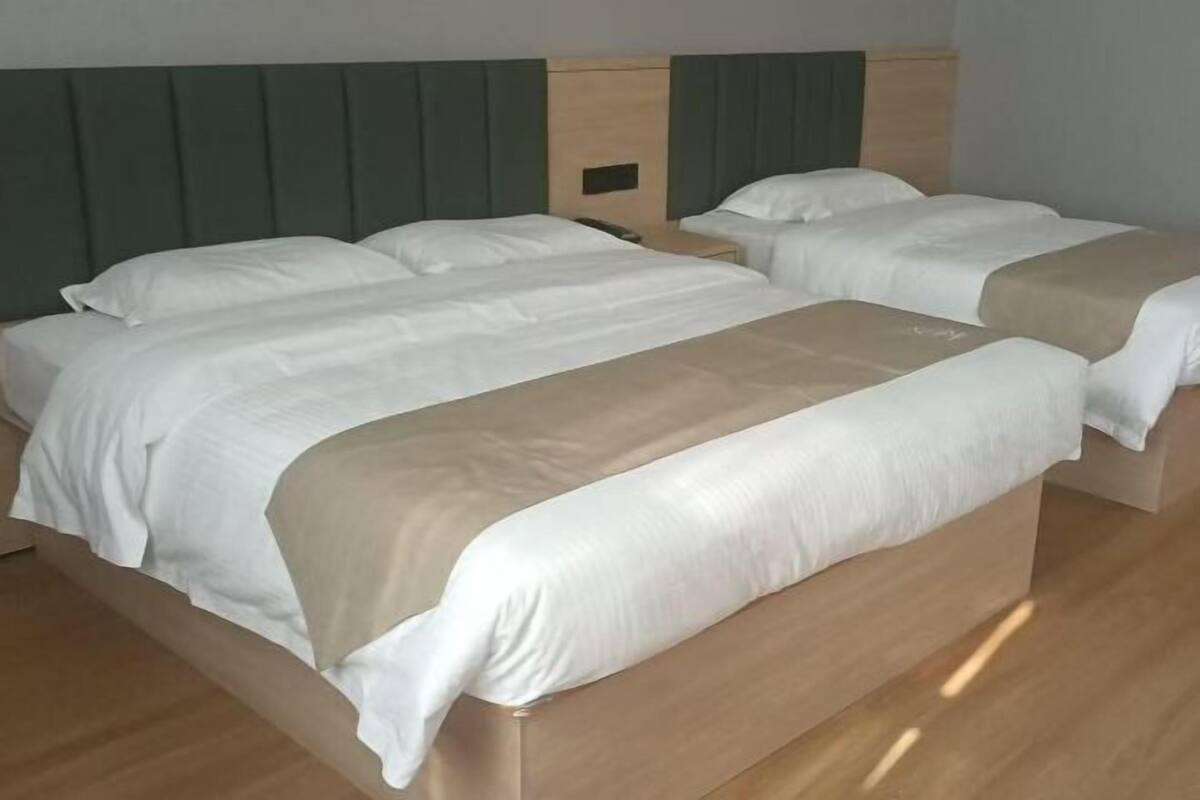 A hotel room with two beds, a wooden headboard, and a small bedside table.