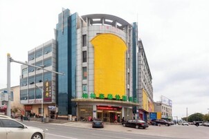 Un hotel de varios pisos con una fachada amarilla destacada y señalización en un idioma extranjero.