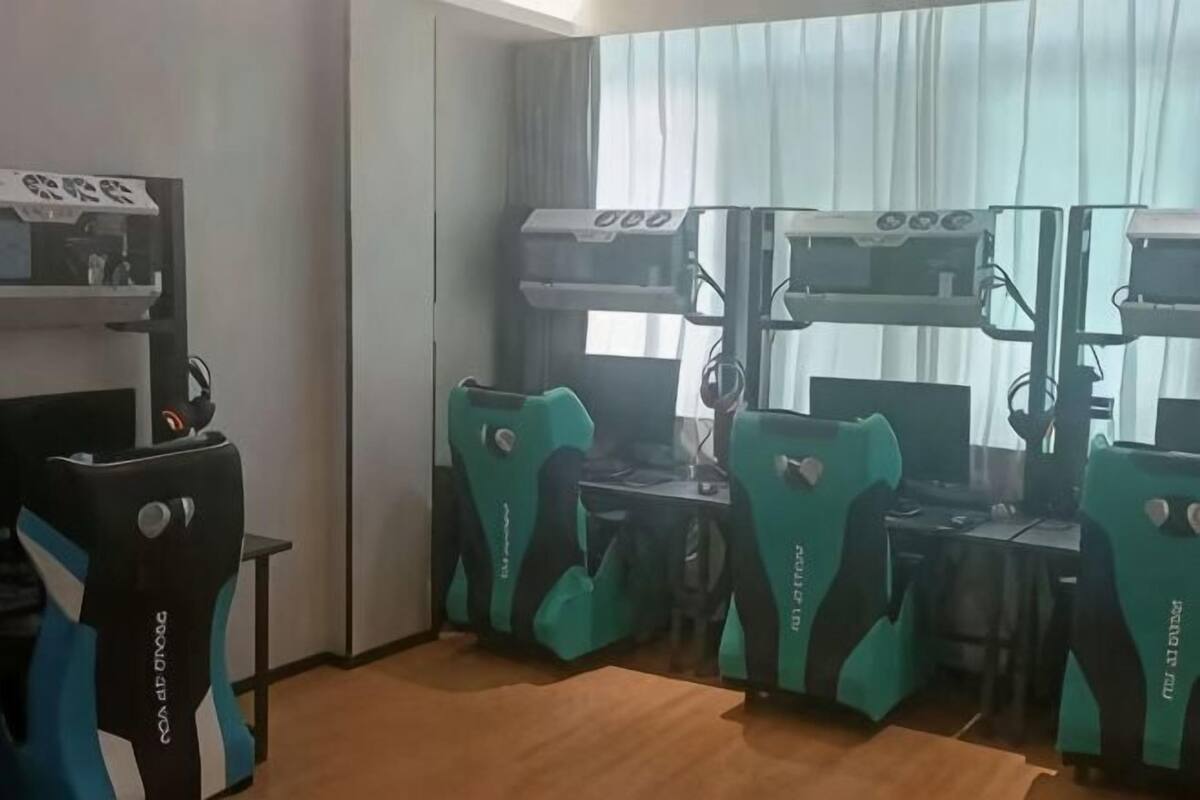 A room with gaming chairs, a desk, and a large screen.