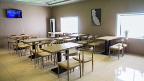 A modern dining area with multiple tables and chairs, a flat-screen TV mounted on the wall, and large windows providing natural light. - GreenTree Inn Smart Choice Hotel (Changzhou Xixiashu Branch) (Huludao)