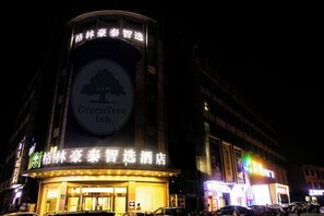 A hotel with a prominent GreenTree Inn sign, a large tree logo, and a well-lit entrance. - GreenTree Inn Smart Choice Hotel (Changzhou Xixiashu Branch) (Huludao)