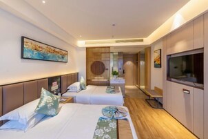 Habitación de hotel con dos camas, televisión, espejo y suelo de madera.