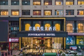 Das Außere des Junyikaiyue Hotels mit einem markanten Eingang und einem gut sichtbaren Schild.