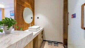 Une salle de bain moderne avec un meuble-lavabo en bois, un grand miroir et un plan de toilette en marbre.