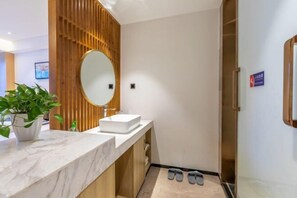 Ein modernes Badezimmer mit einem Holzbadezimmerunterschrank, einem großen Spiegel und einer Marmorarbeitsplatte.