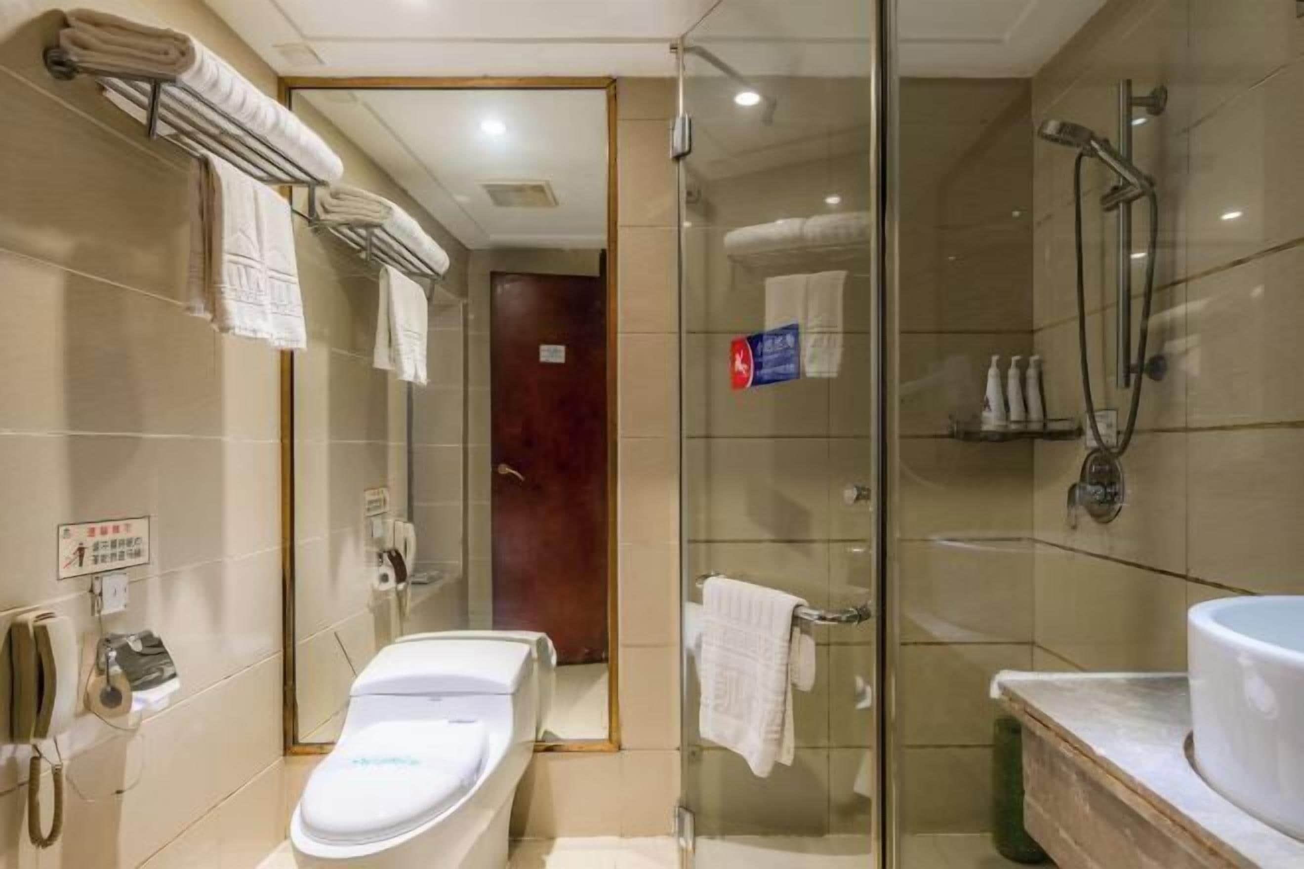 Ein Hotelbad mit Duschkabine, Waschbecken mit Spiegel und Toilette.