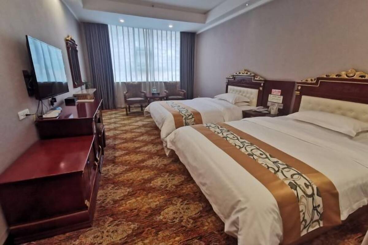 Ein Hotelzimmer mit zwei Betten, einem Fernseher, einem Schreibtisch und einem Stuhl.