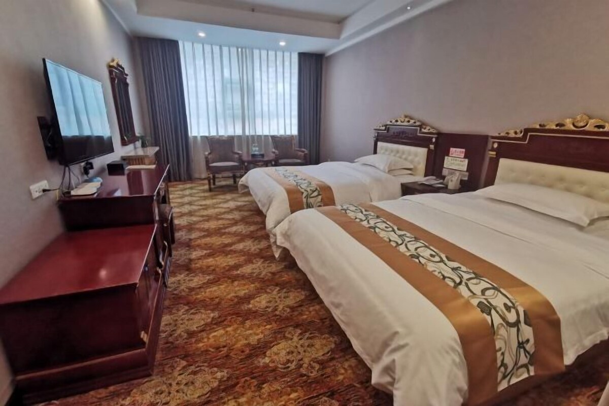 Ein Hotelzimmer mit zwei Betten, einem Fernseher, einem Schreibtisch und einem Stuhl.