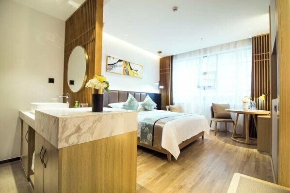 Habitación de hotel con cama, escritorio, silla, tocador con espejo y ventana con cortinas.