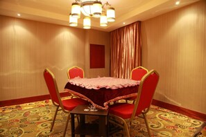 Ein Konferenzraum mit einem Tisch, vier Stühlen, einer Chandelier und einem gemusterten Teppich.