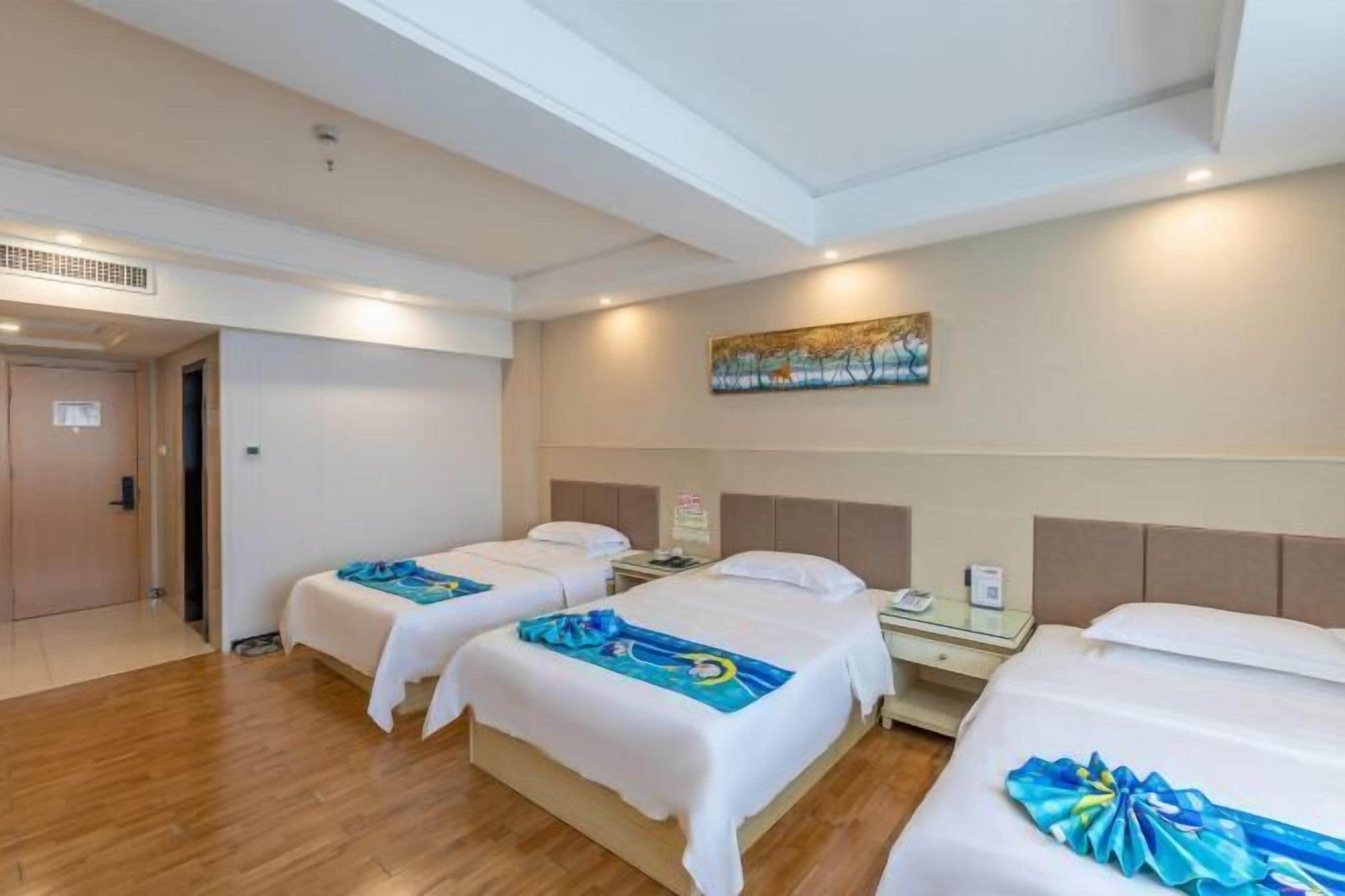 A hotel room with two beds, a painting on the wall, and a door to the left.