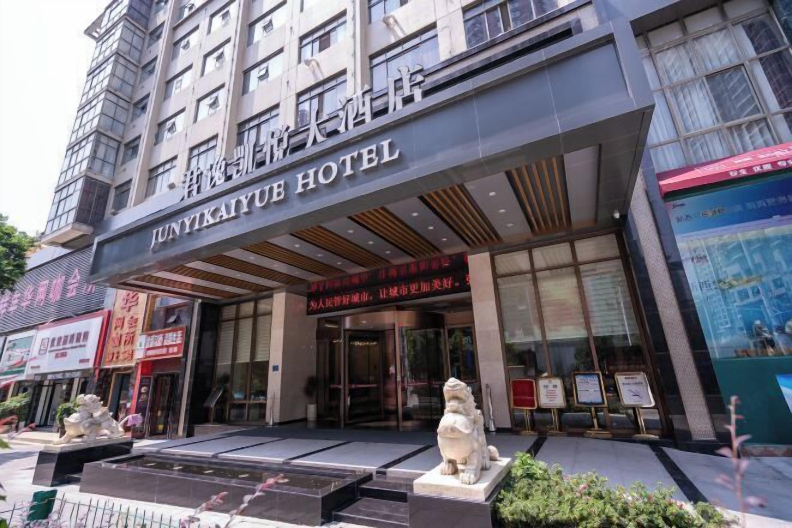The exterior of Junyikaiyu Hotel with a modern facade, large glass windows, and a prominent entrance.