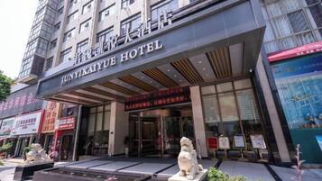 The exterior of Junyikaiyu Hotel with a modern facade, large glass windows, and a prominent entrance.
