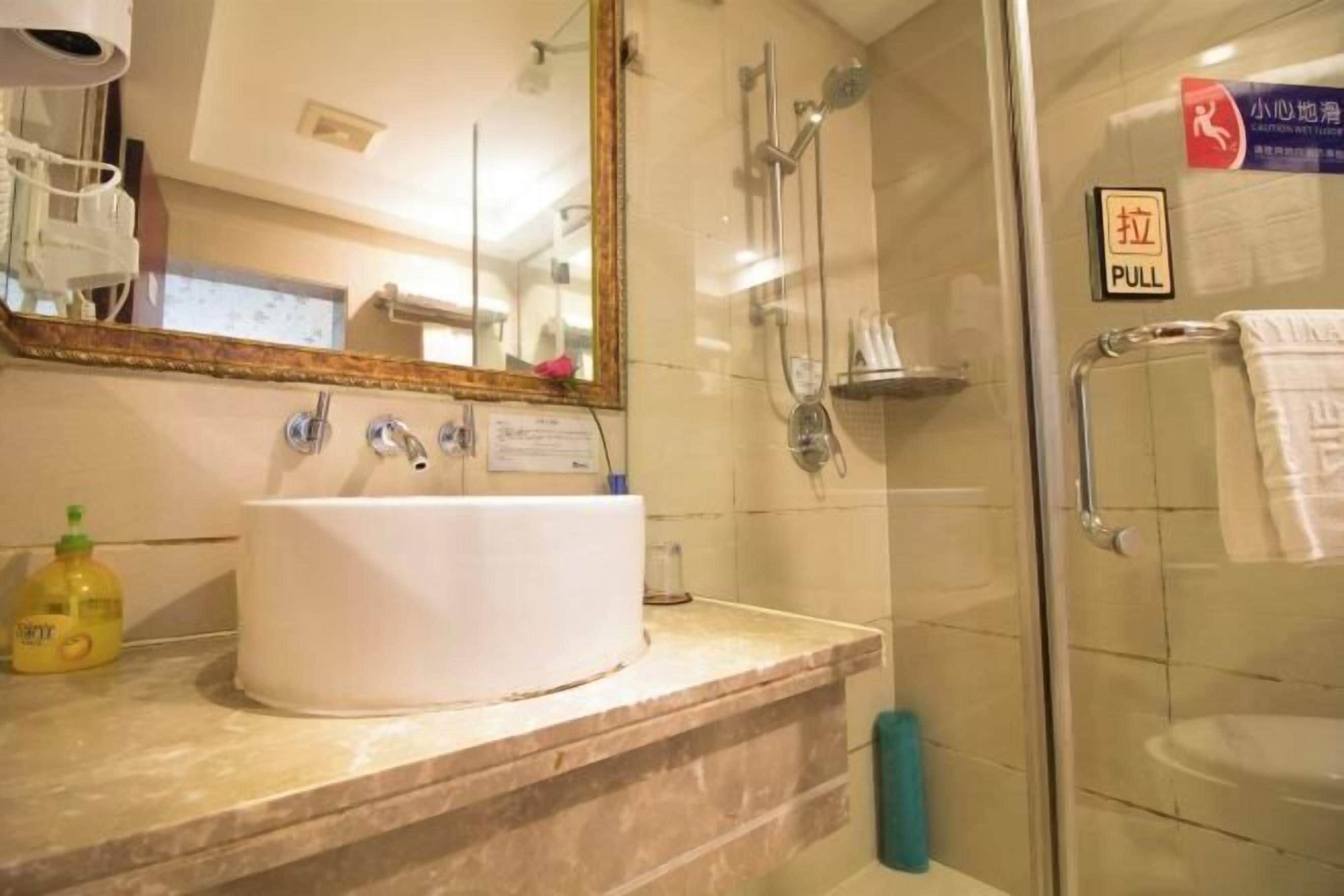 A bathroom with a sink, mirror, and shower.