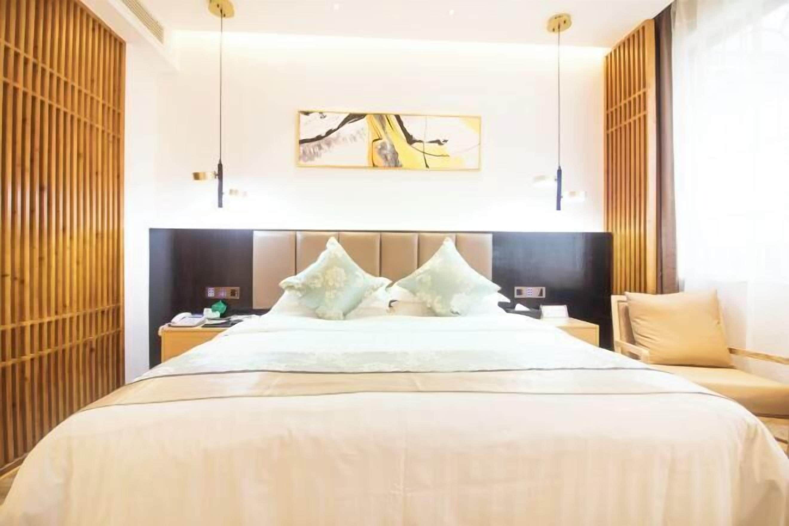 Una habitación de hotel con una cama grande, un cabecero, una mesita de noche, una silla y una obra de arte colgada en la pared.
